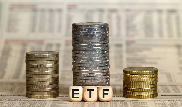 Kocky s nápisom ETF, v pozadí mince naukladané na seba