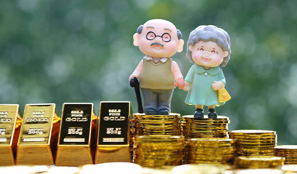 Figúrky seniorov stojace na zlatých minciach a zlatých tehličkách v symbole investovania na dôchodok