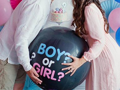 Pár s čiernym balónom naplneným farebnými konfetami na gender reveal party